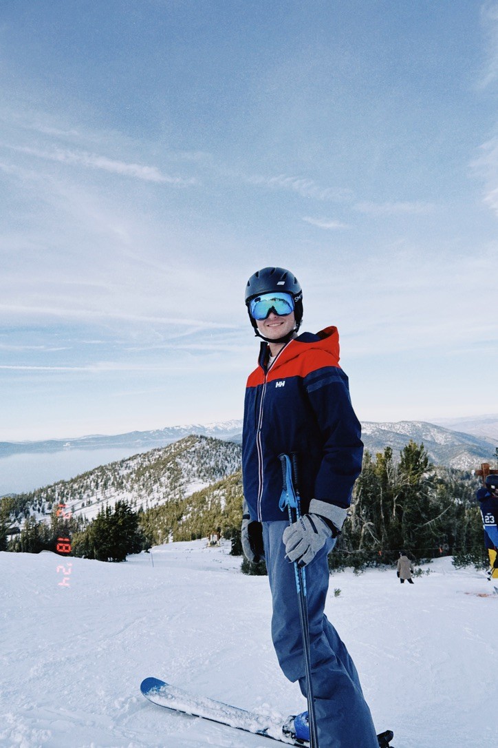 Jake skiing on a snowy mountain slope with alpine terrain visible.
